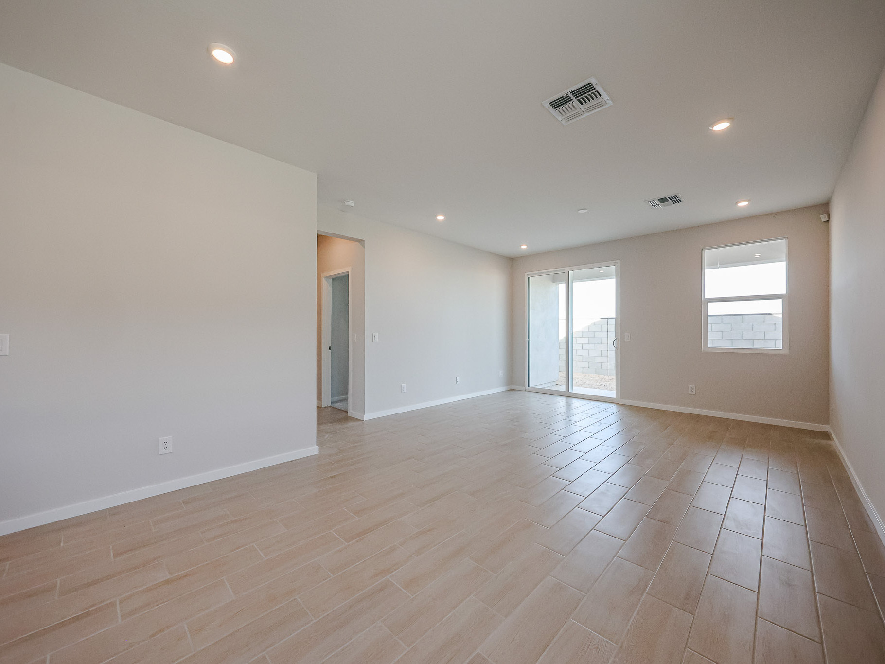 A large empty room with a wood floor and windows.