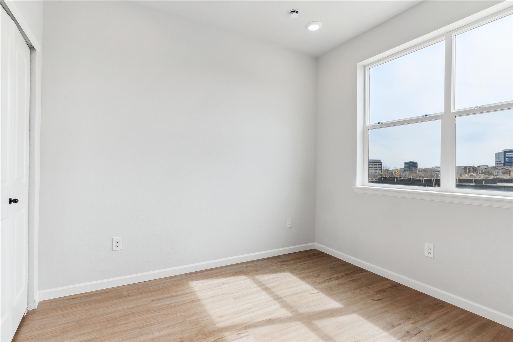 A room with a window and a wood floor.