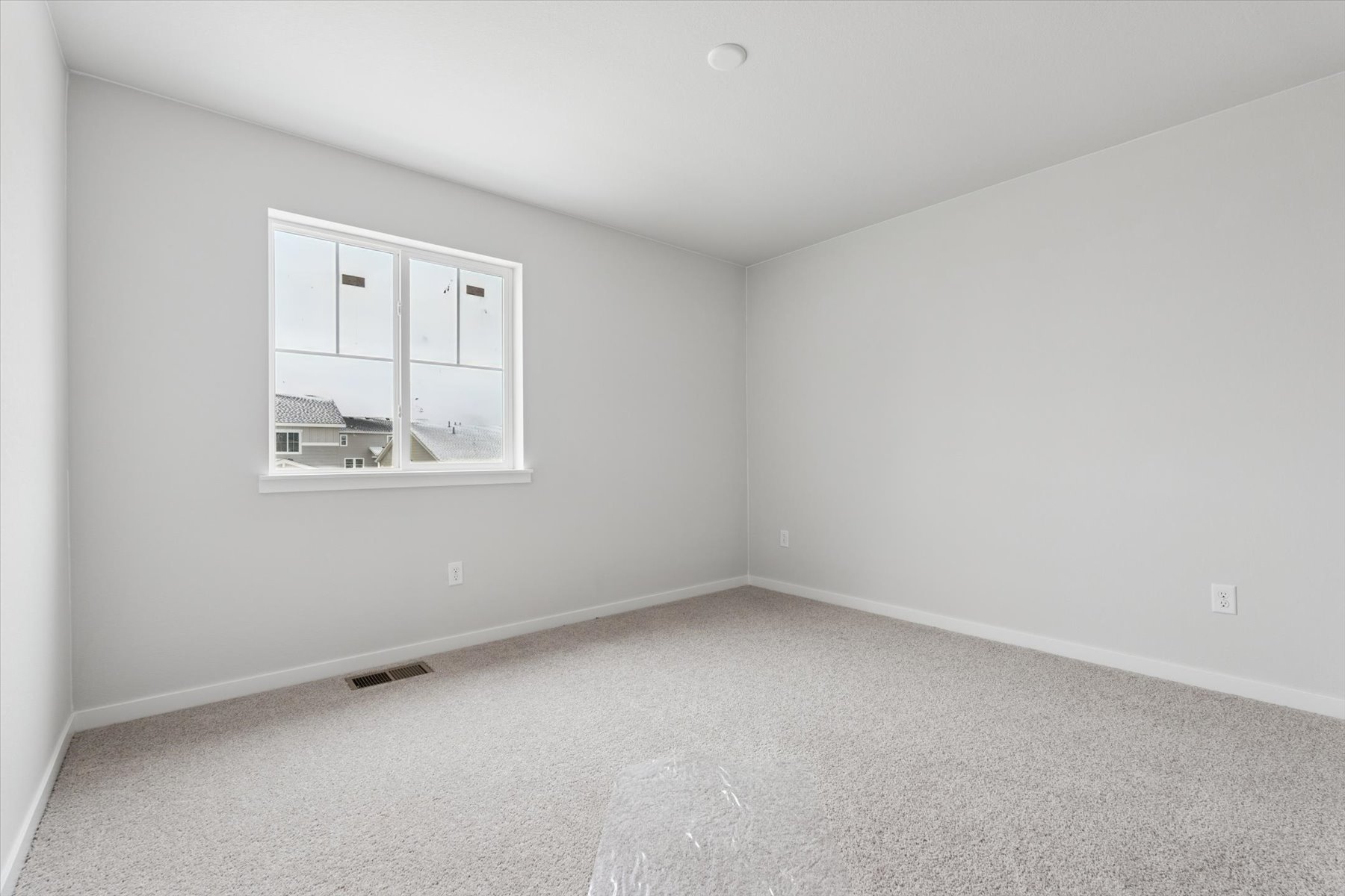 A room with a window and a white wall.