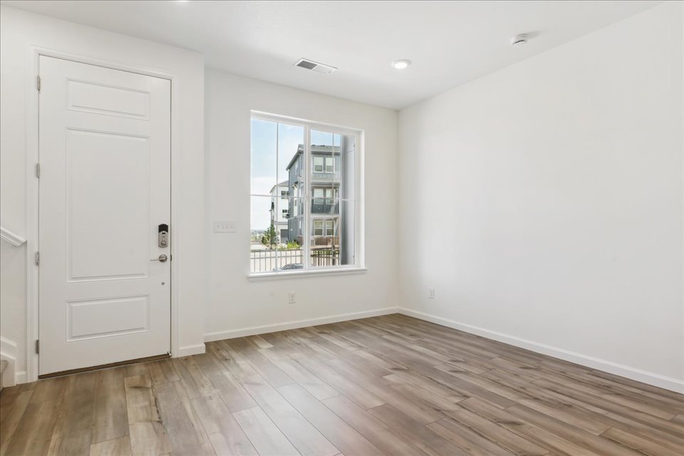A room with a wood floor and a window with a view of a city.