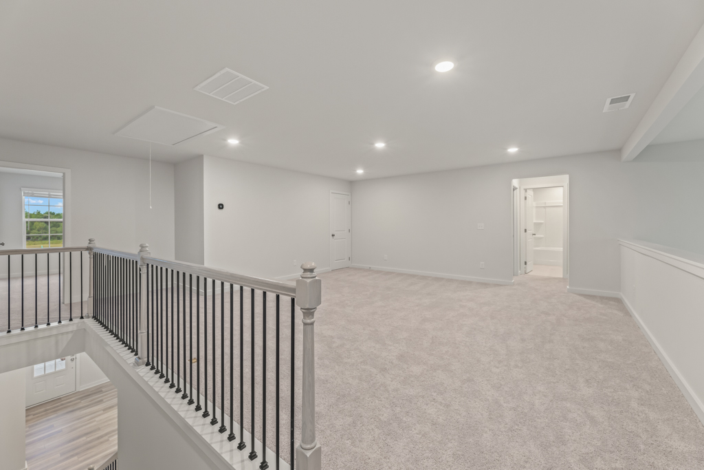 A large white room with a black railing and white walls.