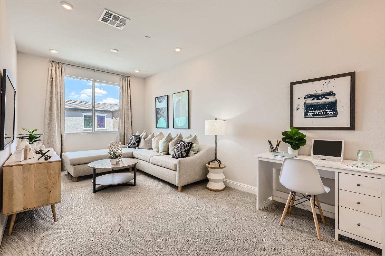 A living room with a white couch and a desk.