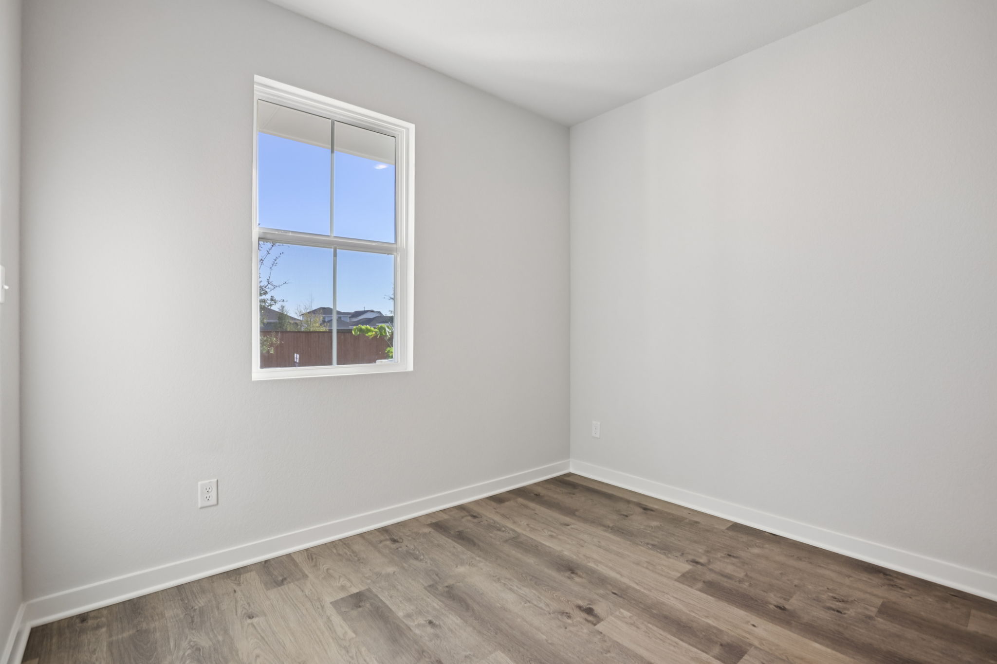 A room with a window and a wood floor.