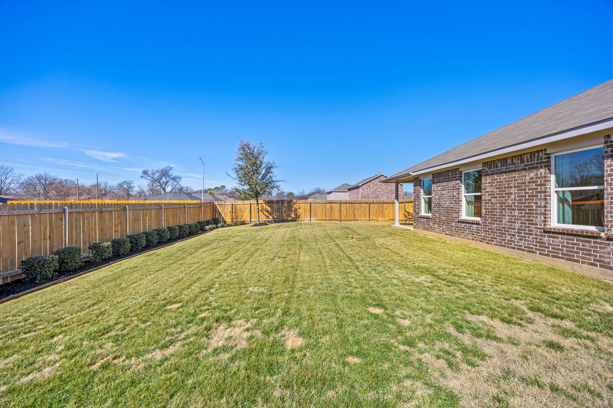 A fenced in yard with a house and trees in the background.