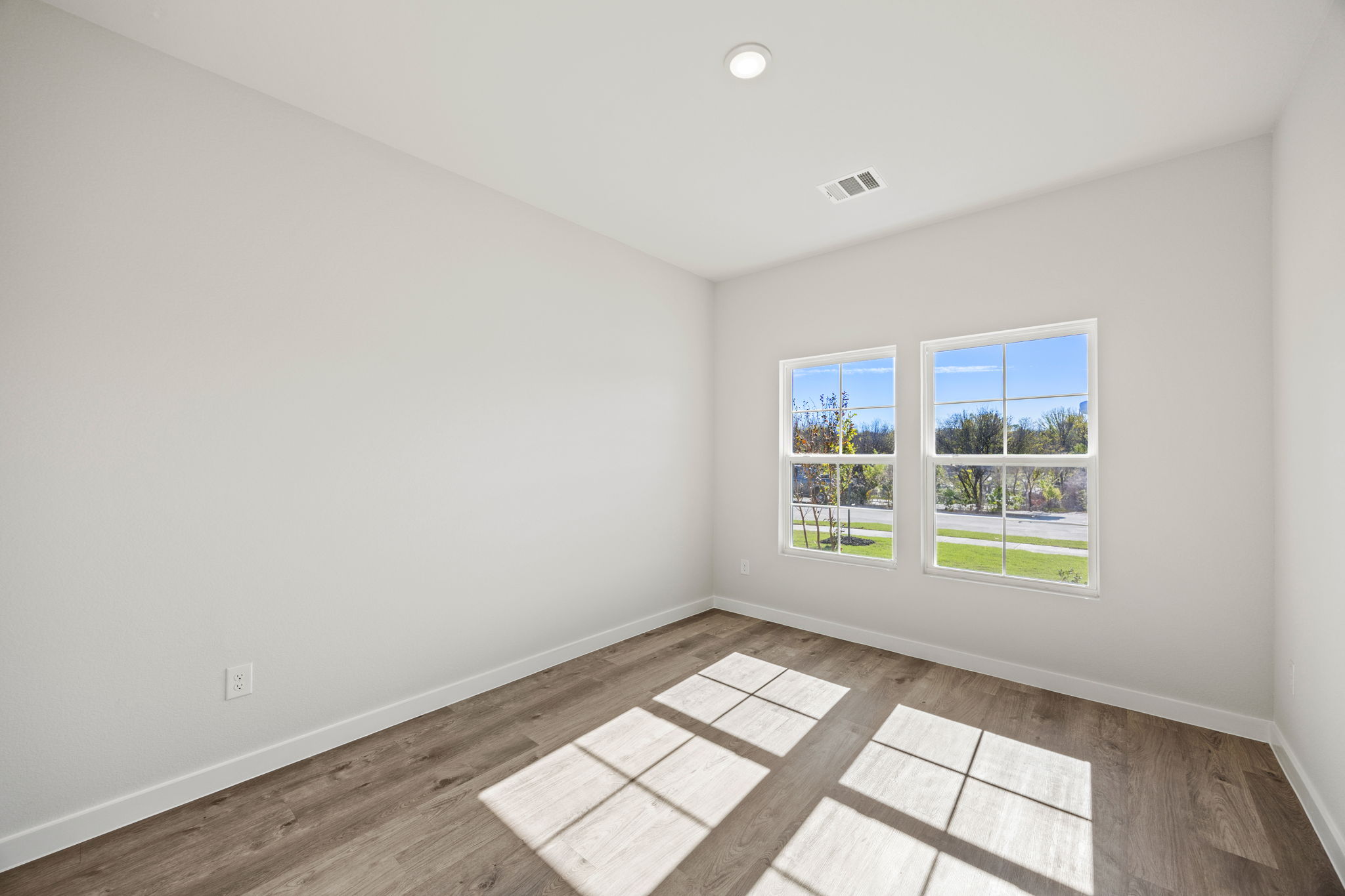 A room with a wood floor and windows.
