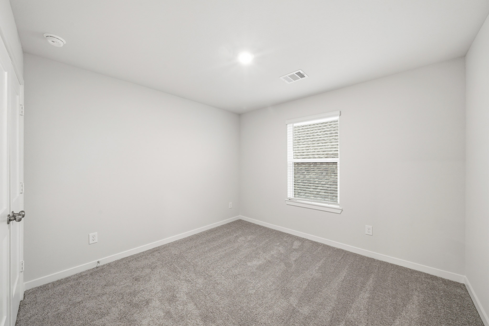 A room with a carpet and a window.