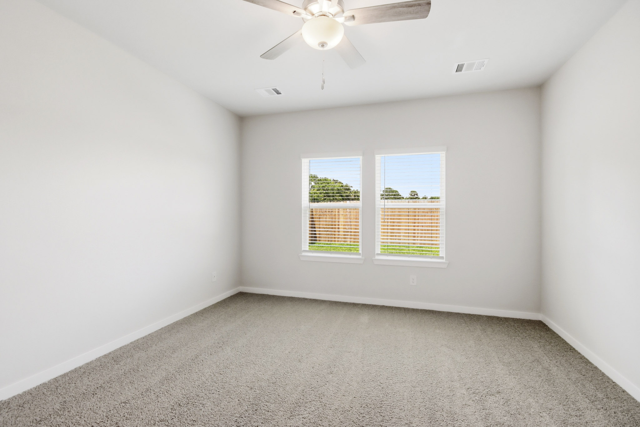 A room with a ceiling fan and a window with blinds.