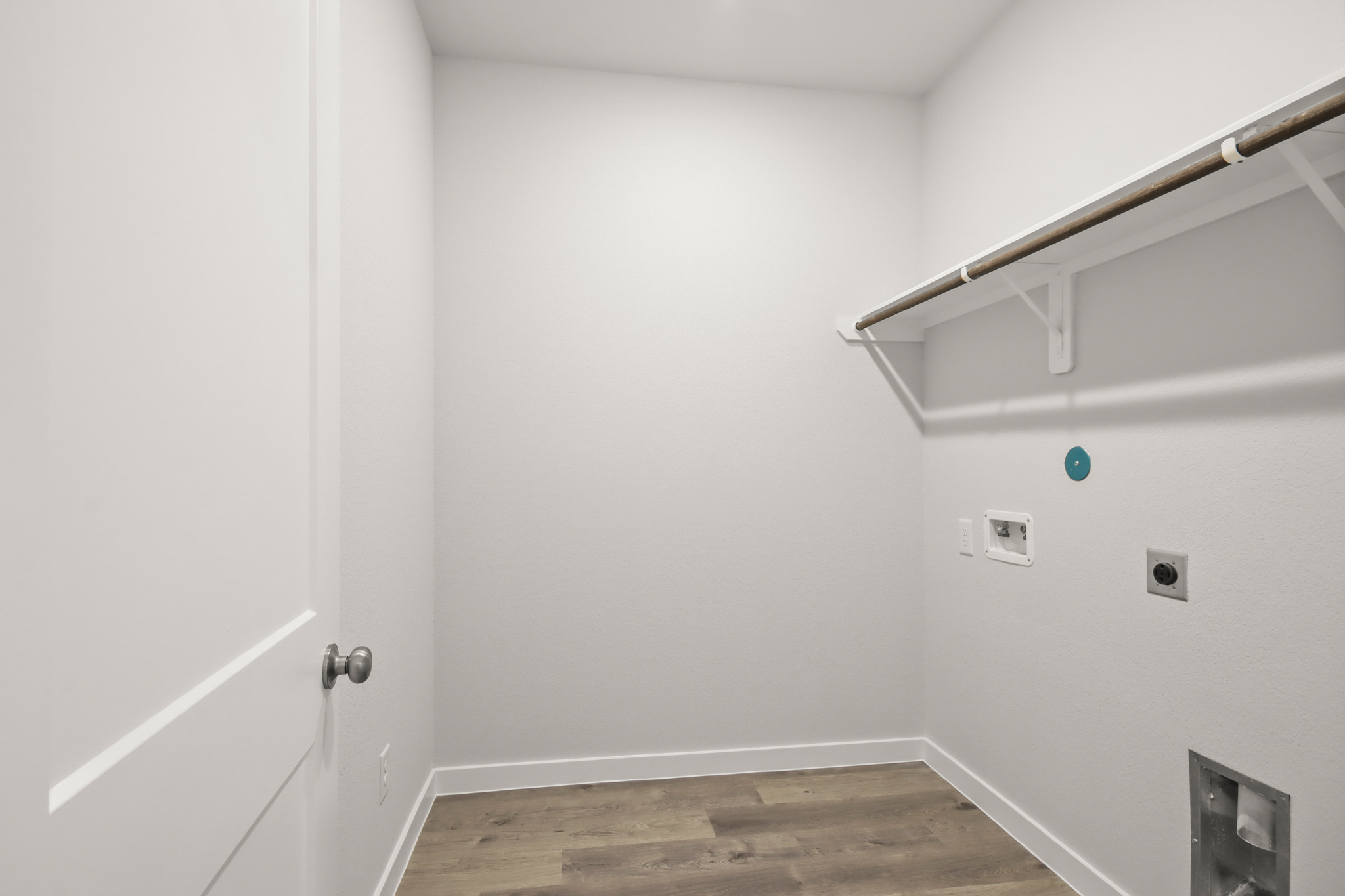 A white room with a wood floor and a white door.