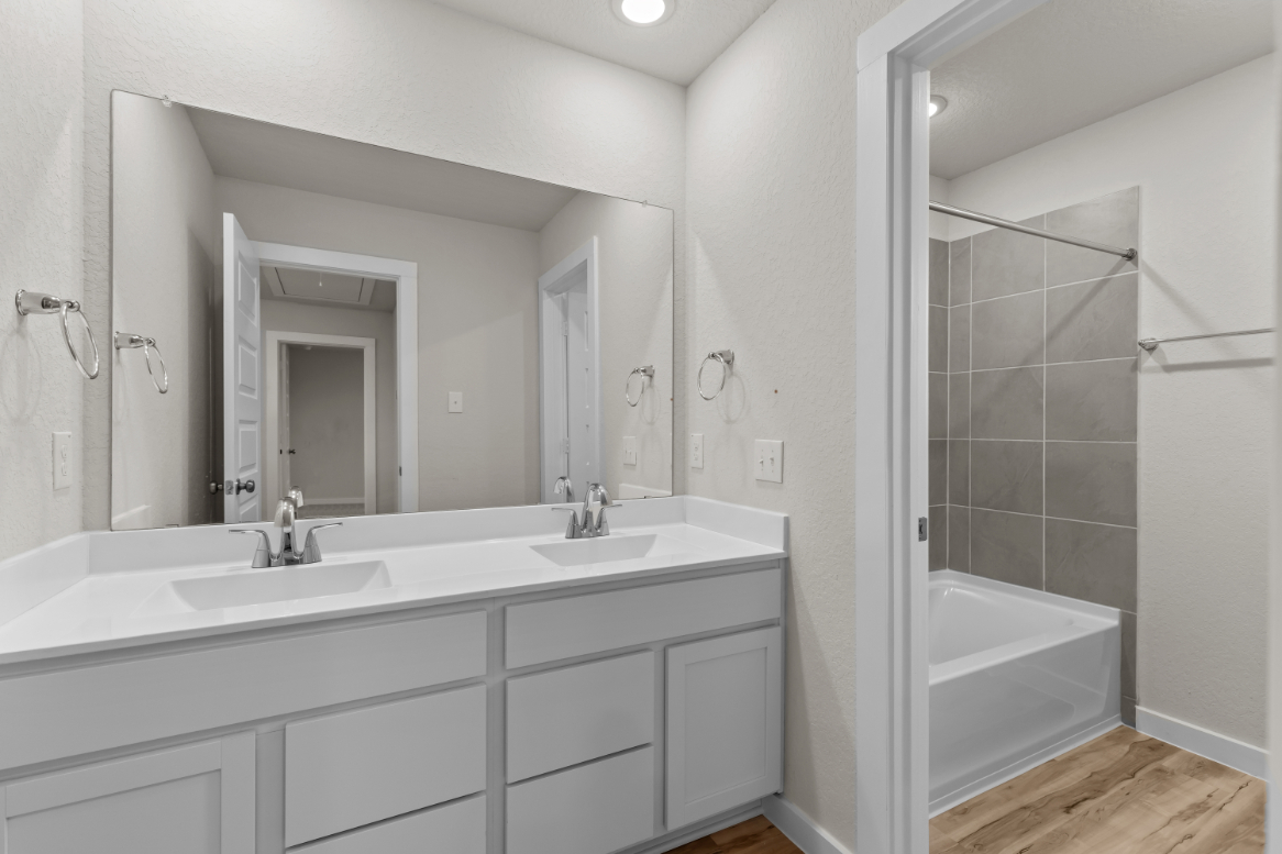A bathroom with a tub sink and mirror.