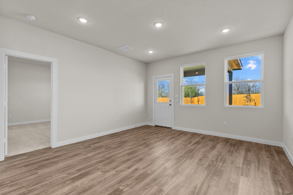 A room with a wood floor and a wood floor with a door and a window with a tree.