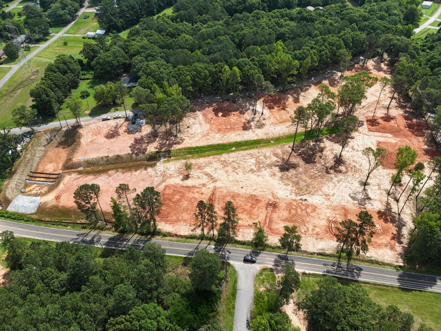 A road with trees and a dirt hill with a road and cars.